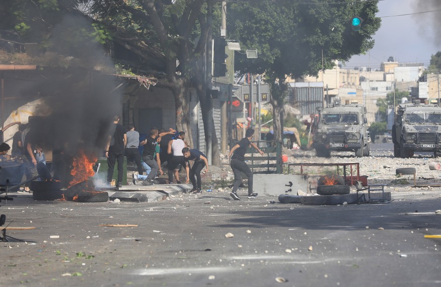 epa10112169 Palestinians clash with Israeli troops during a raid in the West Bank city of Nablus, 09 August 2022. Three Palestinians were killed, on 09 August, when Israeli soldiers blew up a house th ...