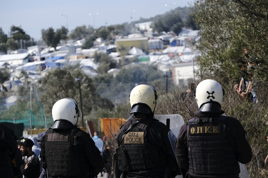 Greek riot police guard during clashes outside the Moria refugee camp on the northeastern Aegean island of Lesbos, Greece, on Monday, March 2, 2020. Thousands of migrants and refugees massed at Turkey ...