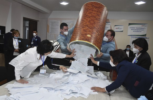 Members of an election commission pulls ballots out of a box preparing to count them at a polling station after the presidential election in Tashkent, Uzbekistan, Sunday, Oct. 24, 2021. Uzbekistan&#03 ...