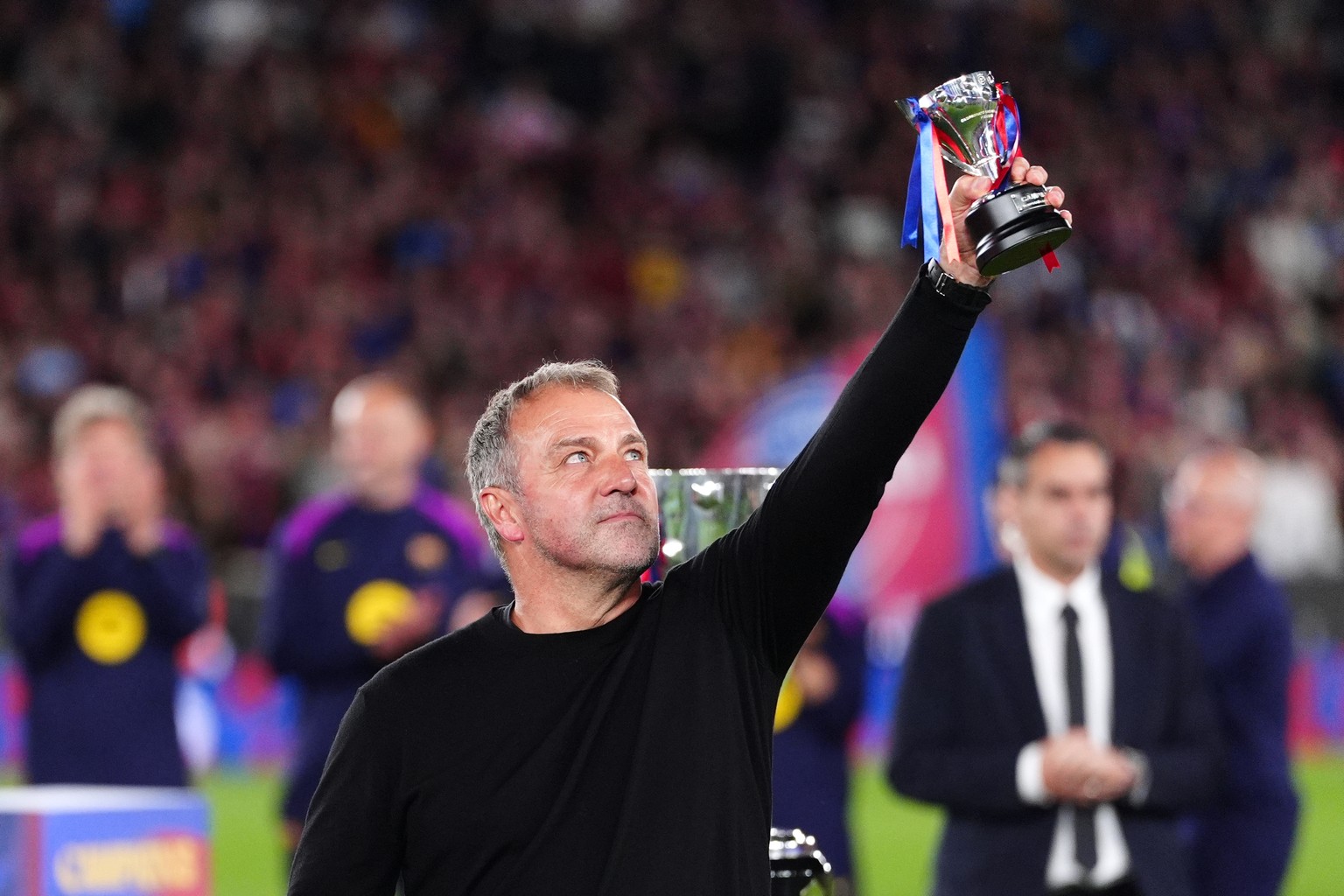 Barcelona head coach Hansi Flick lifts his award to the sky celebrating after defeating Real Madrid 2-0 to win the Spanish La Liga soccer championship with three rounds to spare, in Barcelona, Spain,  ...