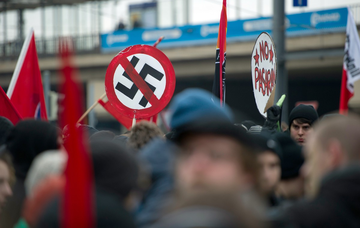 ARCHIV - 18.02.2012, Sachsen, Dresden: Teilnehmer einer Demonstration unter dem Motto "Mit Mut, Respekt und Toleranz gegen Rechtsextremismus" halten ein Schild mit einem durchgestrichenen Ha ...