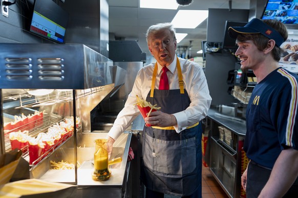 Republican presidential nominee former President Donald Trump, left, serves up french fries as an employee looks on during a campaign stop at a McDonald&#039;s in Feasterville-Trevose, Pa., Sunday, Oc ...