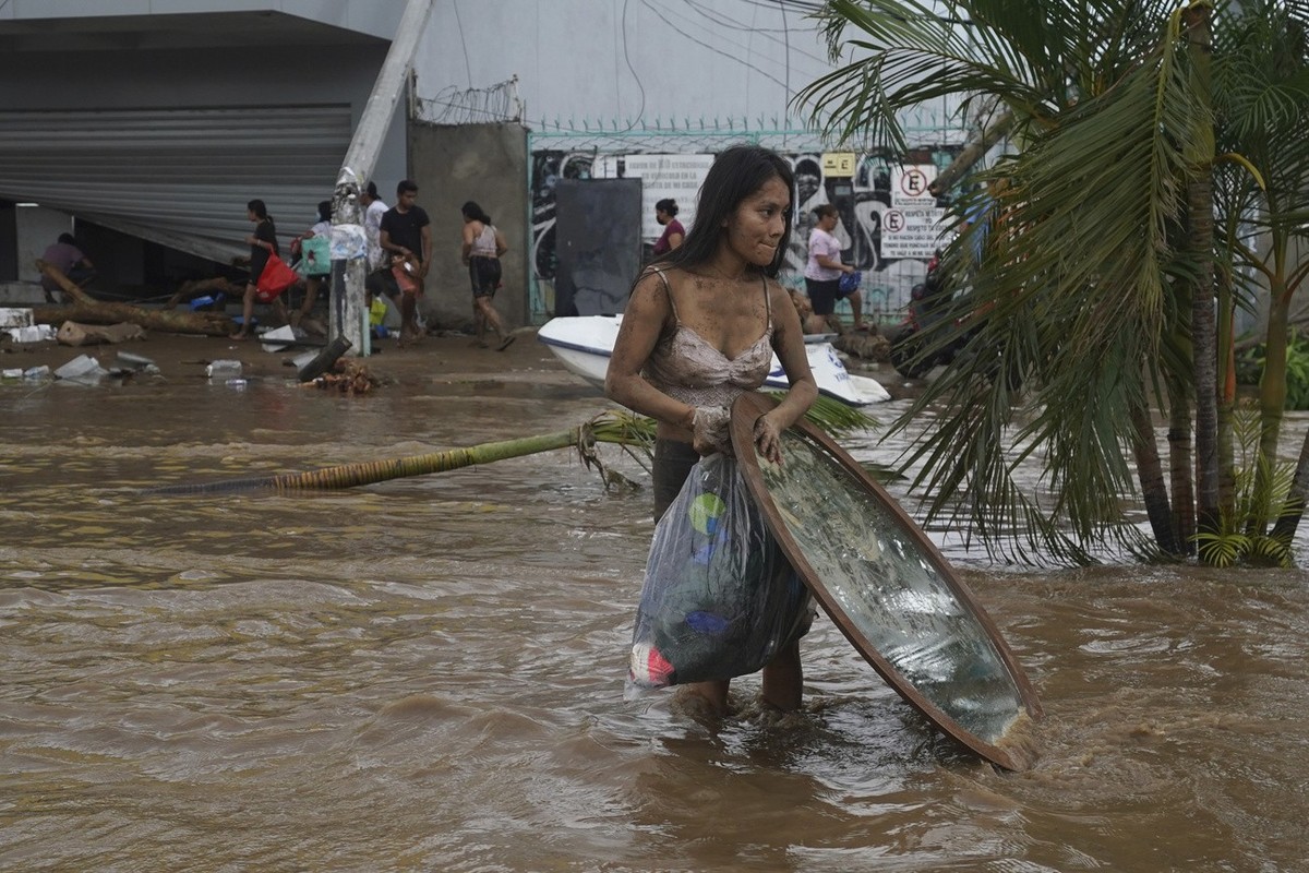 A woman walks away with stuff she looted from a furniture store after Hurricane Otis ripped through Acapulco, Mexico, Wednesday, Oct. 25, 2023. Hurricane Otis ripped through Mexico's southern Pac ...