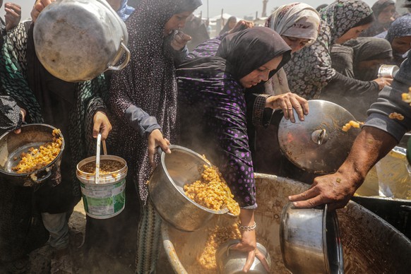 epa12086657 Internally displaced Palestinians gather to receive a portion of food from a charity kitchen, in Jabalia refugee camp, northern Gaza Strip, 09 May 2025. According to the UN Palestinian ref ...