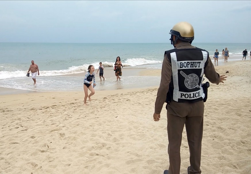 epa07259914 A Thai police officer warns tourists about a swimming ban due to a weather warning at a beach of Koh Samui Island, Surat Thani province, southern Thailand, 03 January 2019. Thai resorts is ...