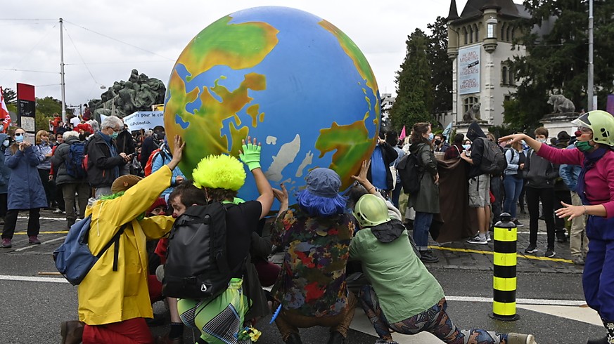 Klimaaktivisten balancieren einen Erdball.