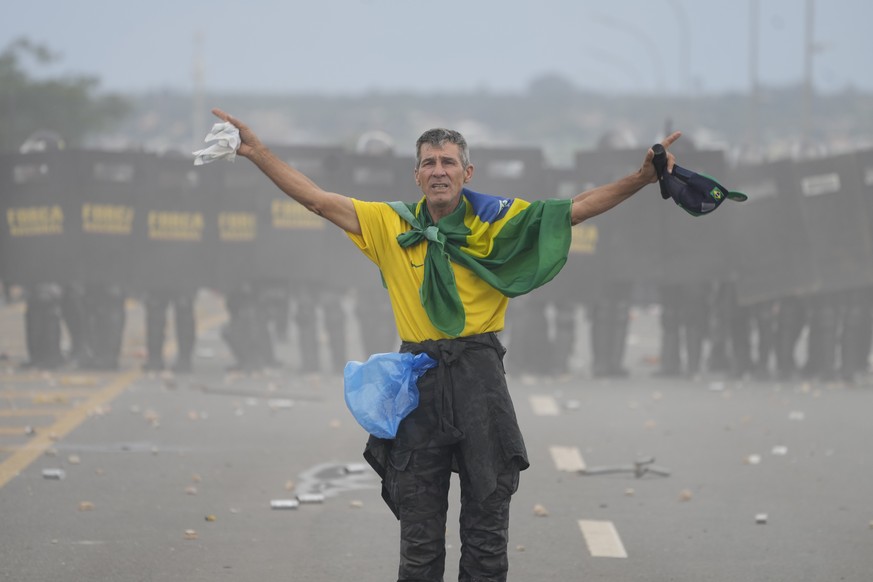 A protester, supporter of Brazil&#039;s former President Jair Bolsonaro, stands in front of a line of police in riot gear, during the storming of the Planalto Palace in Brasilia, Brazil, Sunday, Jan.  ...