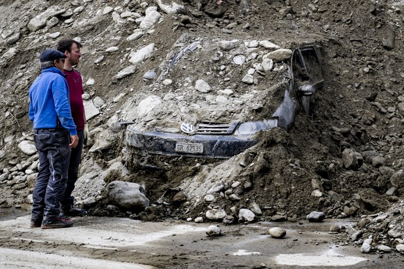 Deux personnes regardent un vehicule recouvert de gravats dans le village haut-valaisan ensevelie ce week-end par une lave torrentielle le mardi 2 juillet 2024 a Saas-Grund. (KEYSTONE/Jean-Christophe  ...