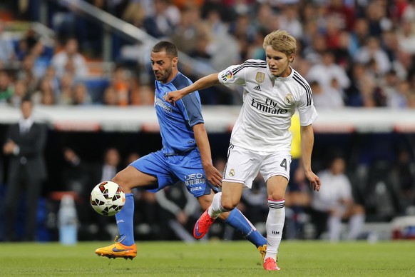 Real Madrid&#039;s Martin Odegaard from Norway, right, duels for the ball with Getafe&#039;s Lacen, during a Spanish La Liga soccer match between Real Madrid and Getafe at the Santiago Bernabeu stadiu ...