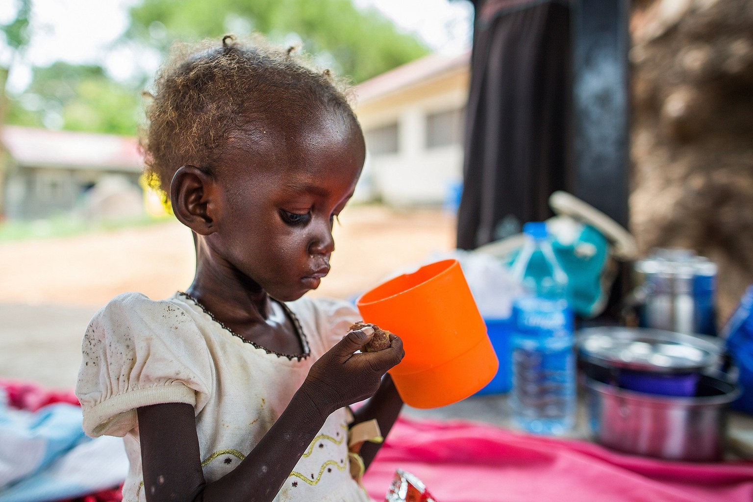 Maria John, 2, who has been diagnosed with severe acute malnutrition, drinks a ration of therapeutic milk, which is rich in nutrients and easy to digest, at a UNICEF supported inpatient stabilization  ...