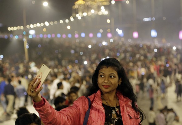 An Indian woman takes a selfie as she celebrates the arrival of the new year at marine drive in Mumbai, India, Tuesday, Jan 1, 2019. (AP Photo/Rajanish Kakade)