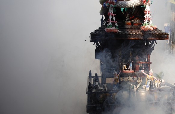 epa10482911 A local shrine is seen in the middle of the smog after a health officer sprayed chemicals to kill mosquitos for the health precaution against dengue fever, inside a community in Bangkok, T ...