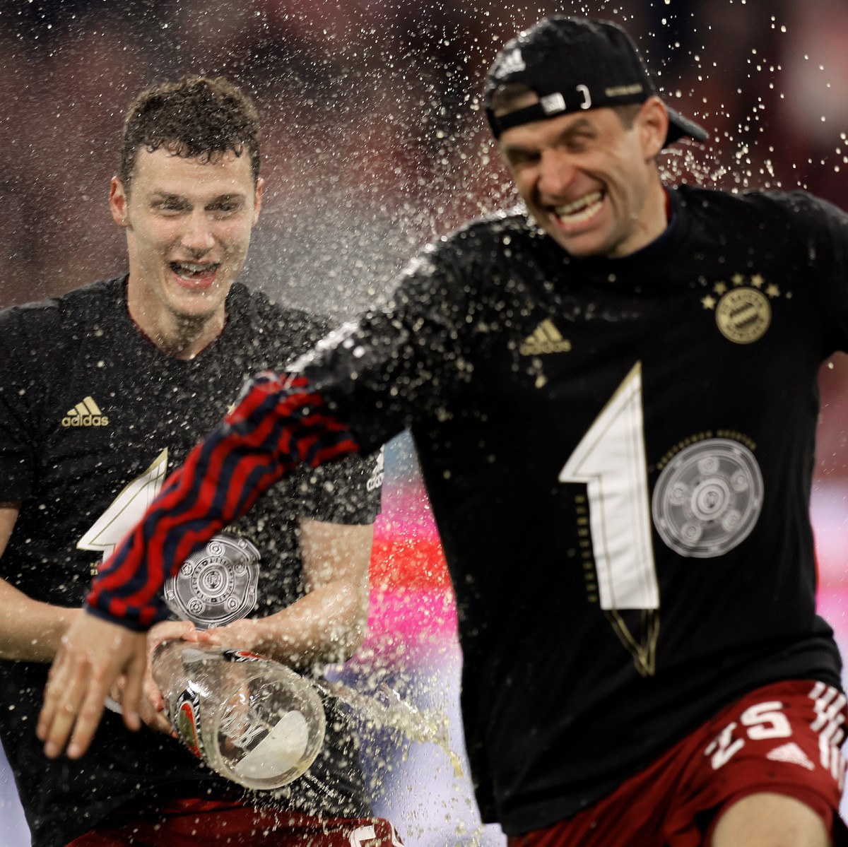 epa09904957 Bayern's Benjamin Pavard (L) and Thomas Mueller (R) celebrate the tenth consecutive Bundesliga title, after winning the German Bundesliga soccer match between FC Bayern Muenchen and B ...