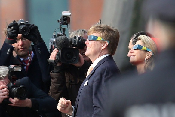 epa04670840 Queen Maxima and King Willem-Alexander of the Netherlands look at the solar eclipse through special glasses at the Fish Market inÂ Hamburg, Germany, 20 March 2015. The royal couple is on a ...