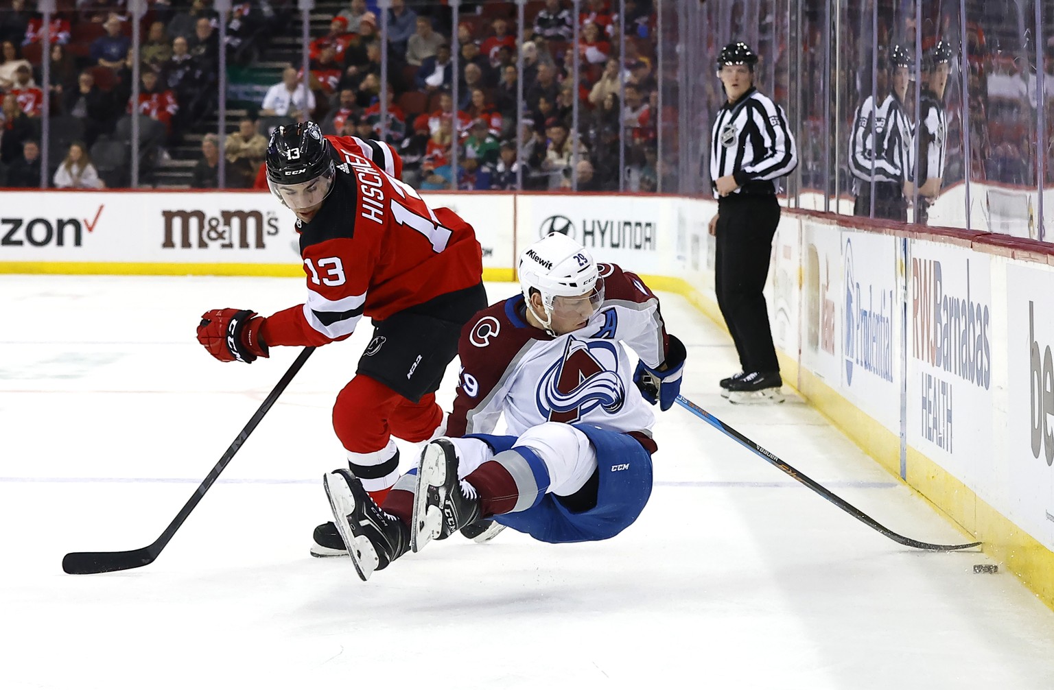 New Jersey Devils center Nico Hischier (13) and Colorado Avalanche center Nathan MacKinnon (29) compete for the puck during the first period of an NHL hockey game Tuesday, Feb. 6, 2024, in Newark, N.J ...