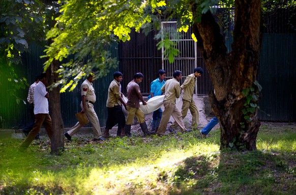 Polizisten und Mitarbeiter des Zoos entfernen die Leiche des getöteten Studenten.