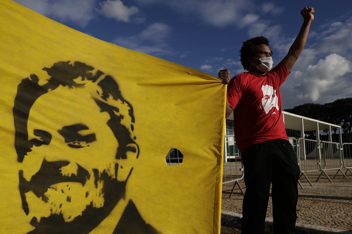 A Worker Party member shows his support during a demonstration outside the Supreme Court while holding on to a banner featuring Brazil's former President Luiz Inacio Lula da Silva, in Brasilia, B ...