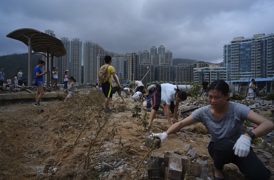 People clean debris from Typhoon Mangkhut on the waterfront in Hong Kong, Monday, Sept. 17, 2018. Hong Kong and southern China hunkered down as strong winds and heavy rain from Typhoon Mangkhut lash t ...