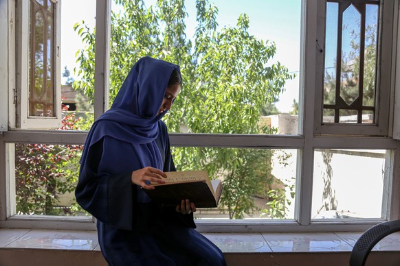 epa11388877 Soura Afazai, reads a book at her home as she hopes to attend the Kankur exams (university entrance exams), in Kabul, Afghanistan, 04 June 2024. As the 2024 Kanur exam (university entrance ...