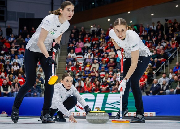 Switzerland skip Xenia Schwaller, center, delivers a stone against Team Canada as lead Selina Rychiger, left, and third Selina Gafner, right, sweep during the gold medal draw at the World Women's ...