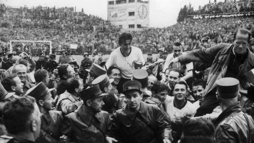 Nach dem WM-Finalspiel am 4. Juli 1954 in Bern werden der deutsche Captain Fritz Walter, Mitte, und Trainer Sepp Herberger, rechts, im Triumph auf den Schultern von begeisterten Anhaengern vom Spielfe ...