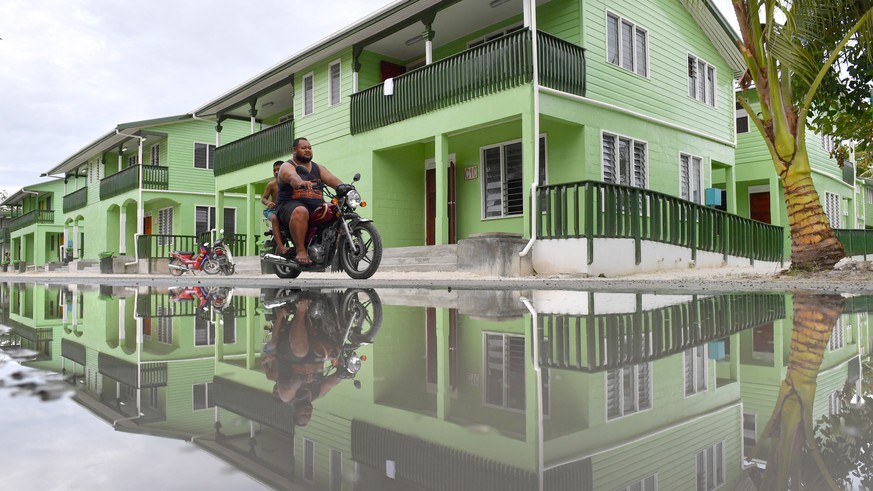 epa07770648 A man riding a motorbike is seen reflected in a puddle of water in Funafuti, Tuvalu, 13 August 2019. The 50th Pacific Islands Forum and Related Meetings, fostering cooperation between gove ...