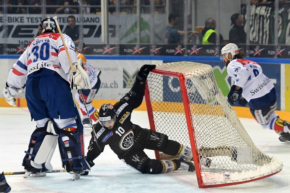 Zurich&#039;s goalkeeper Lukas Flueeler, left, fights for the puck with Luganoâs player Alessio Bertaggia, right, during the fifth match of the playoff final of the National League of the ice hockey ...