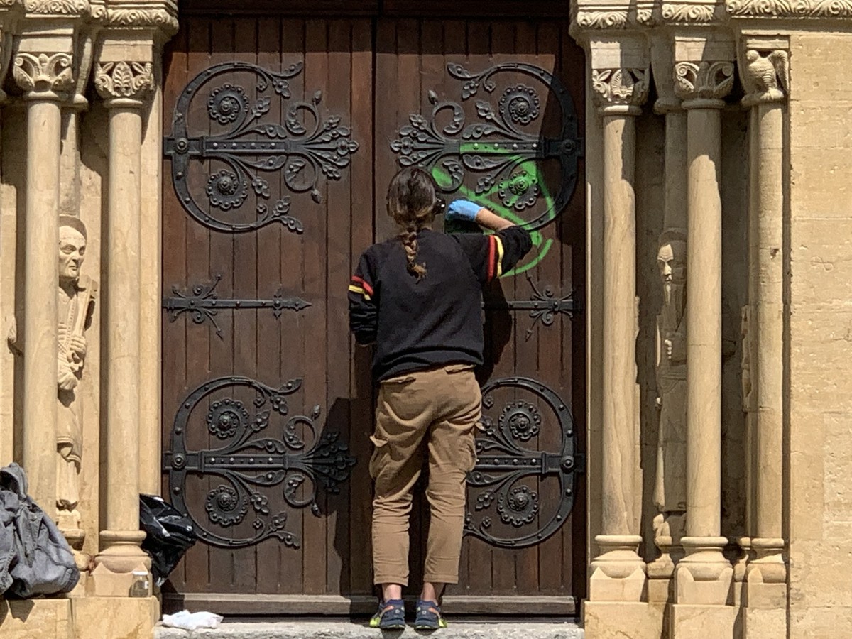 Nettoyage de ce qui ressemble à une «croix sataniste». L'une des portes de la collégiale de Neuchâtel.
