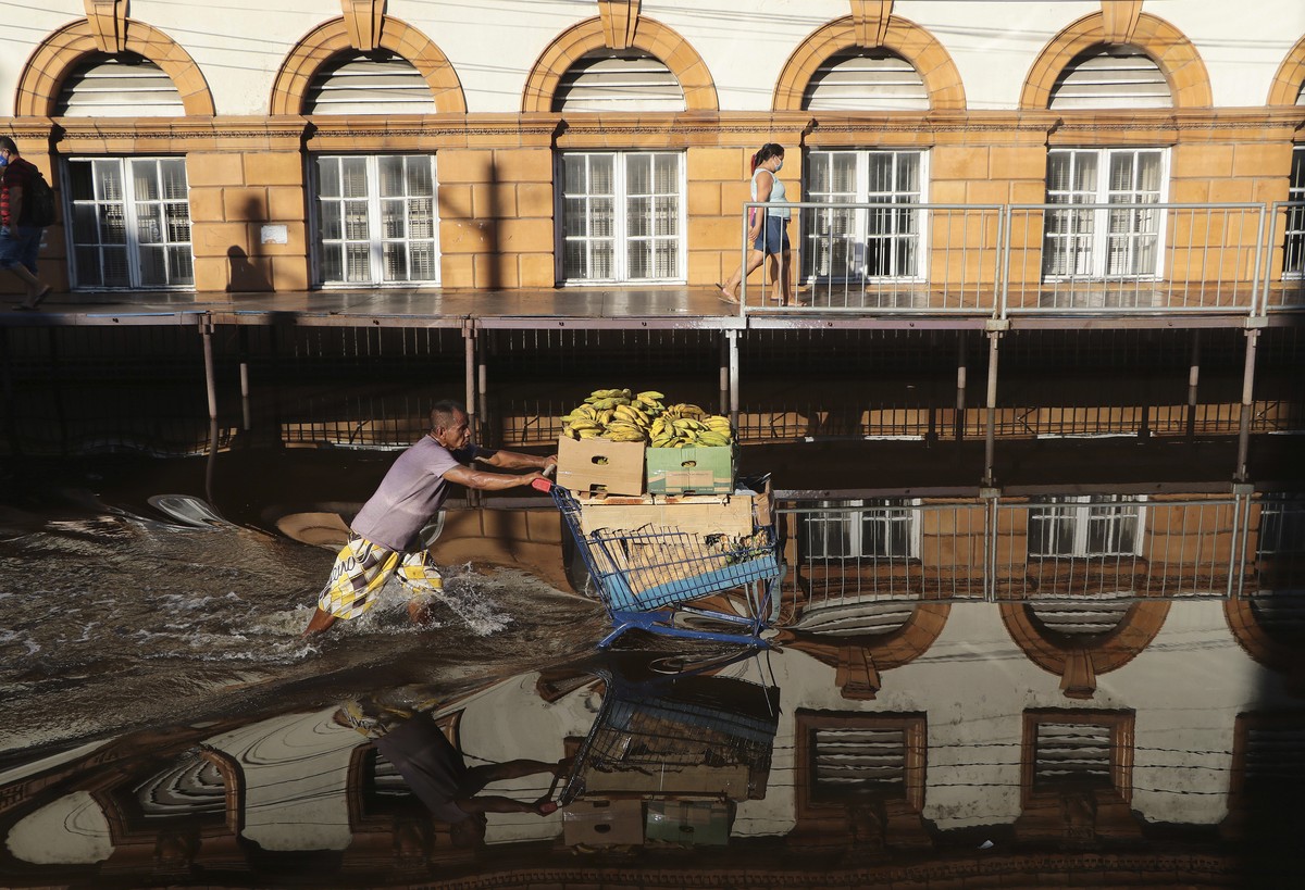 A man pushes a shopping cart loaded with bananas through a street flooded by the Negro River in downtown Manaus, Amazonas state, Brazil, Tuesday, June 1, 2021. Rivers around Brazil's biggest city ...