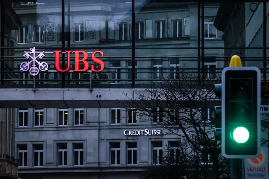 The logos of the Swiss banks Credit Suisse and UBS are displayed on different buildings behind traffic lights in Zurich, Switzerland on Sunday March 19, 2023. (KEYSTONE/Michael Buholzer).