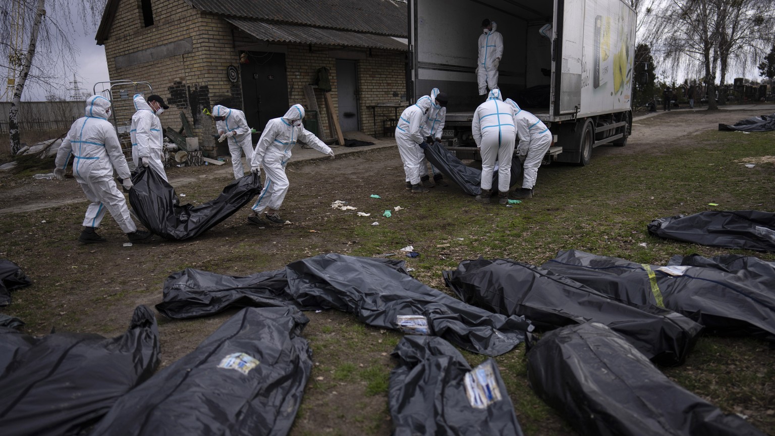 FILE - Volunteers load bodies of civilians killed in Bucha onto a truck to be taken to a morgue for investigation, in Bucha on the outskirts of Kyiv, Ukraine, Tuesday, April 12, 2022. (AP Photo/Rodrig ...