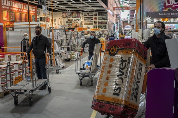 epa08362296 Customers wearing face masks in a hardware store in Vienna, Austria, 14 April 2020. From today on, non essential stores with a shop area under 400 square meters, hardware stores, garden ce ...