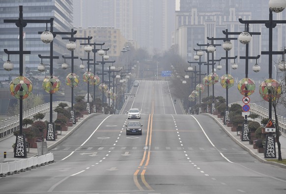 In this photo released by China's Xinhua News Agency, cars drive down a nearly empty street in Xi'an in northwestern China's Shaanxi Province, Thursday, Dec. 23, 2021. China is redoubling efforts to control new virus outbreaks with a lockdown of the 13 million residents of the northern city of Xi'an following a spike in coronavirus cases. (Shao Rui/Xinhua via AP)