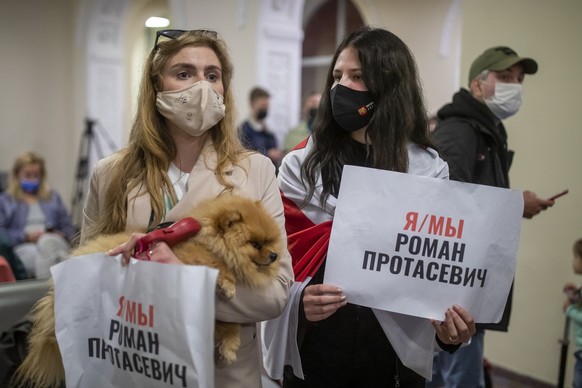 Women one of them wearing an old Belarusian national flag hold posters reading &quot;I&#039;m/we&#039;re Raman Pratasevich&quot; as they wait to see passengers of the Ryanair plane with registration n ...