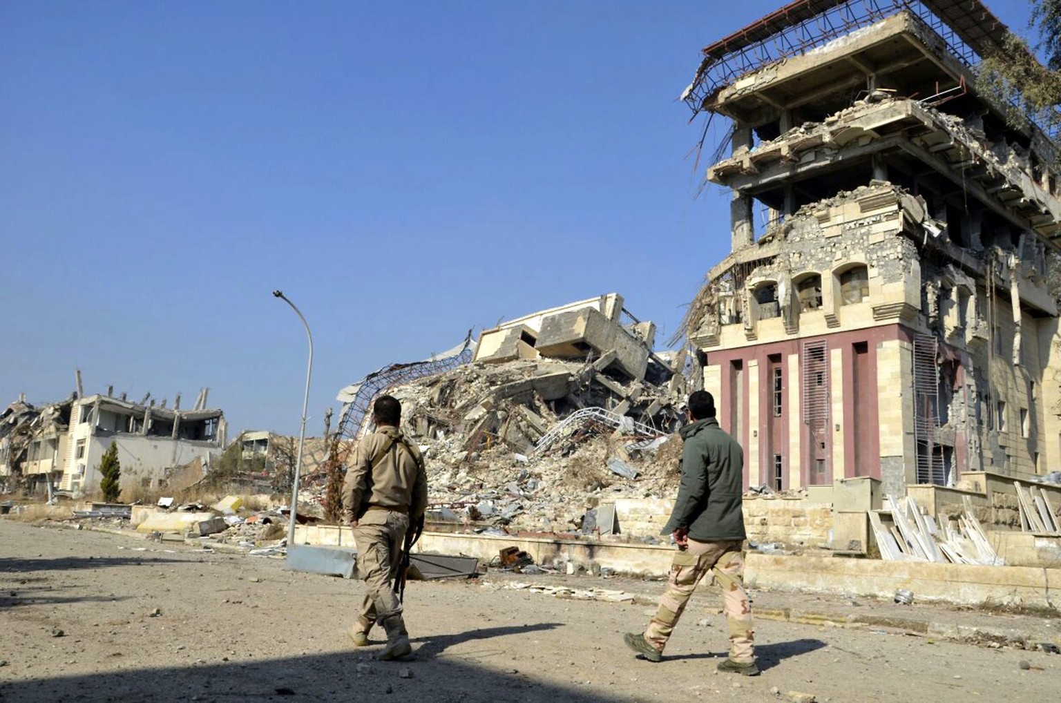 epa05773121 Two Iraqi soldiers walks next to a destroyed building at the university of Mosul in eastern Mosul, north of Iraq, 05 February 2017. Hundreds of volunteers from Mosul have joined to a popul ...