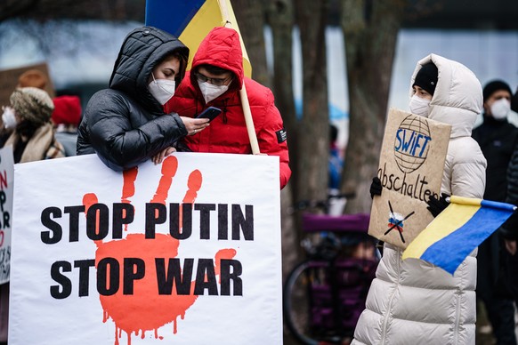 epa09784528 Ukrainian supporters demonstrate with a placard reading ?stop Putin, stop war? in front of the Chancellery in Berlin, Germany, 25 February 2022. Russia launched a military operation agains ...
