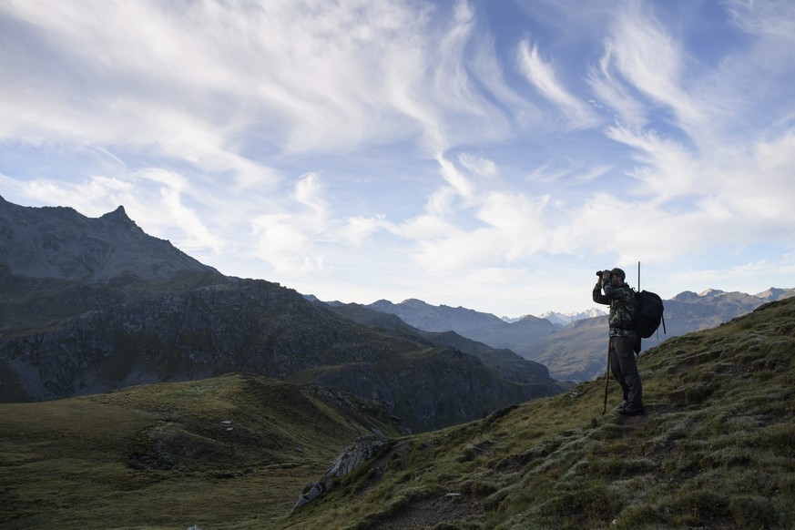 epa05521967 A hunter looks through his binoculars for game at the start of the hunting season on the Alp Flix in Surses, canton Grisions, Switzerland, 03 September 2016. EPA/GIAN EHRENZELLER