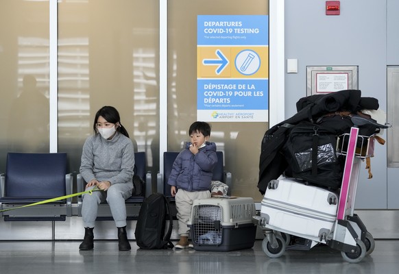 A family waits to travel to the United States of America at Pearson International Airport during the COVID-19 pandemic in Toronto, Friday, Dec. 3, 2021. New travel testing and restrictions have been p ...