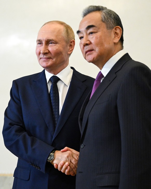 epa11600059 Russian President Vladimir Putin (L) shakes hands with Chinese Central Foreign Affairs Commission Office Director, Foreign Minister Wang Yi after a meeting with high-ranking BRICS official ...