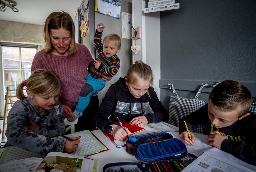 Katja Heimann helps her children with studies in their home in Eisemroth, central Germany, Thursday, March 25, 2021. One year into the coronavirus pandemic, Katja Heimann is still trying to keep her s ...
