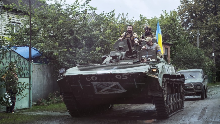 epa10188667 Ukrainian servicemen ride an armoured personnel carrier (APC) with a national flag at a street in the recently recaptured city of Izyum, Kharkiv region, northeastern Ukraine, 16 September  ...