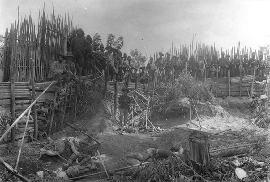 Soldaten der niederländischen Kolonialarmee posieren vor getöteten Dorfbewohnerinnen und Dorfbewohnern in Kuta Reh, Sumatra. Aktuelle Schätzungen gehen davon aus, dass auf dem 1904 durchgeführten Feld ...