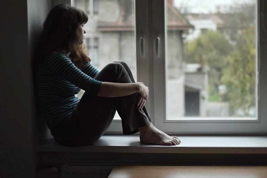 Frau sitzt in Fenster, Quarantäne