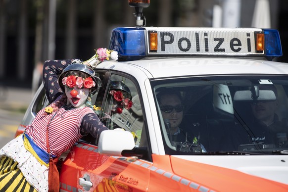 epa07539696 A protester dressed a clown poses next to a police car as she marches to mark Labor Day in Zurich, Switzerland, 01 May 2019. Labour Day or May Day is observed all over the world on the fir ...