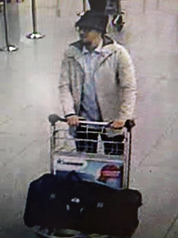 epa05226012 A handout photograph provided by Belgian Federal Police shows a CCTV grab of a suspect in the Zaventem airport attack in Brussels, Belgium, 22 March 2016. A surveillance camera at Zaventem airport in Brussels captured footage of the alleged perpetrators of the explosions that took place earlier the day. It reveals two men dressed in black and both wearing one glove on their left hand, which according to La Libre Belgique could have served to conceal the detonators. The third, dressed in a white jacket and wearing a black hat, is being 'actively pursued' in the meantime, according to Belgian newspapers.  EPA/BELGIAN FEDERAL POLICE / HANDOUT BEST QUALITY AVAILABLE HANDOUT EDITORIAL USE ONLY/NO SALES