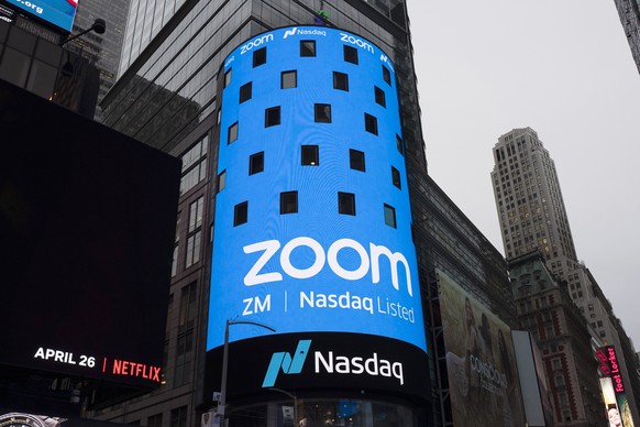 FILE - This April 18, 2019 file photo shows a sign for Zoom Video Communications ahead of the company's Nasdaq IPO in New York.  The video conferencing service is cutting some 1,300 jobs, or about…
