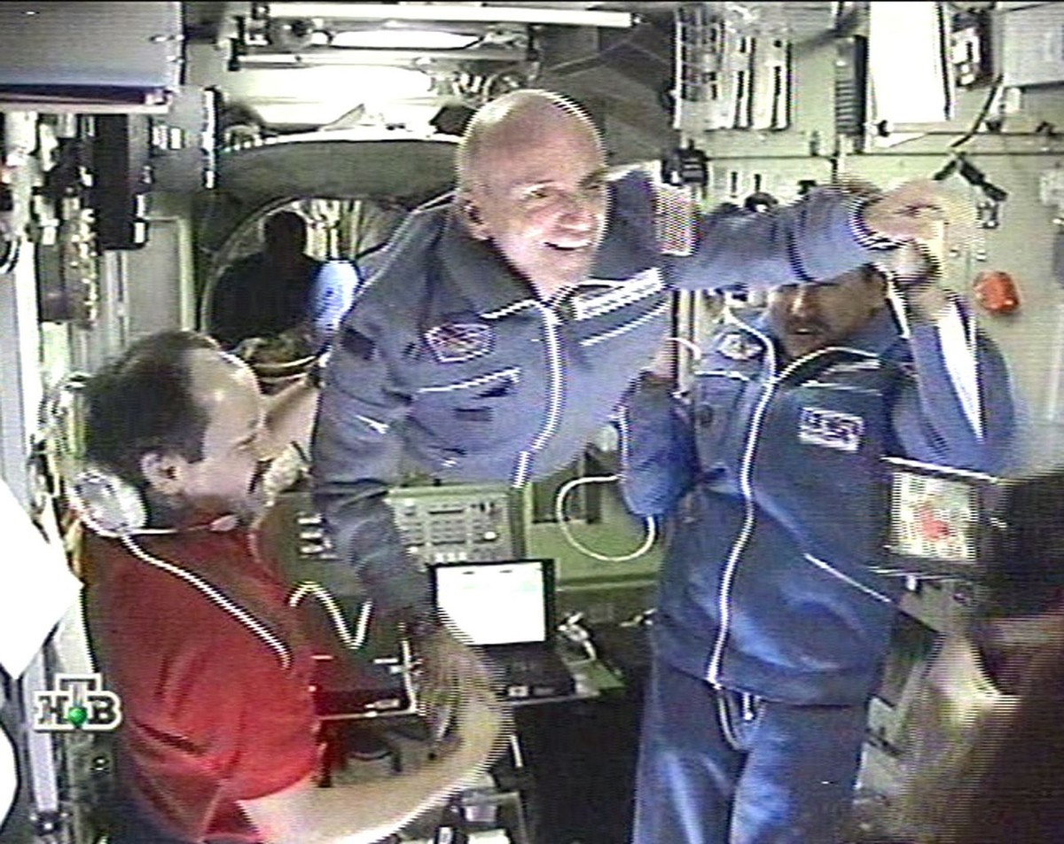 TV-grab taken from the Russian NTV channel shows Russian cosmonauts Talgat Musabayev (R) and Yuri Usachev (L) helping first-ever space tourist Dennis Tito (C) to enter the International Space Station  ...