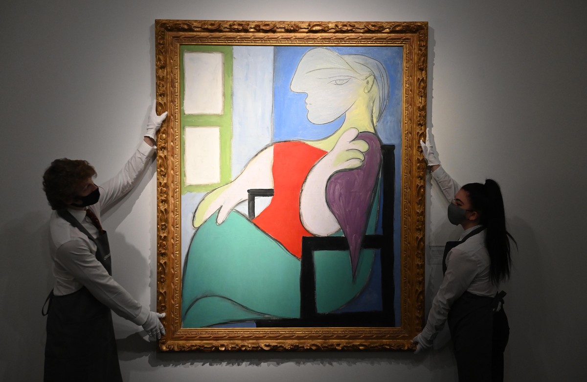 epa09152178 Art handlers pose with the work 'Femme assise pres d'une fenetre (Marie-Therese)' by Pablo Picasso (L) and 'Composition: No. II, with Yellow, Red and Blue' by Piet ...