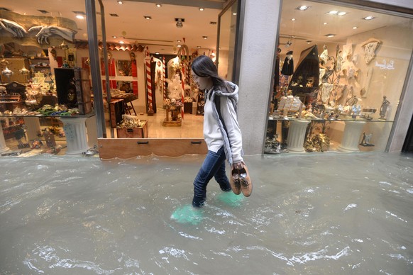 A woman walks in a flooded street of Venice, Italy, Monday, Oct. 29, 2018, as, according to city officials, 70 percent of the lagoon city has been flooded by waters rising 149 centimeters (more than 5 ...