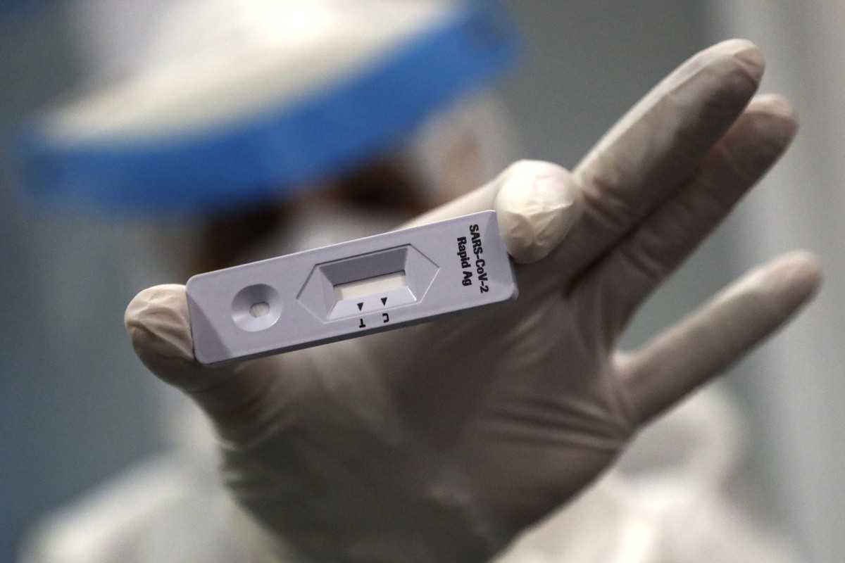 An employee of a new Lufthansa corona quick test center shows the test device into the camera at the airport in Munich, Germany, Thursday, Nov. 12, 2020. Lufthansa starts the first test runs for compr ...